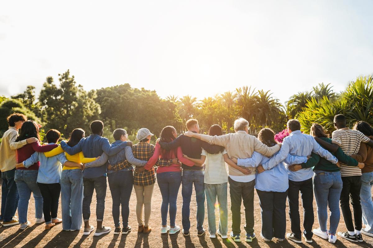 16 people with their backs to the camera, holding each other in a line